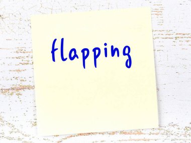 Kanat çırpmayla ilgili hatırlatma kavramı. Tahta duvarda üzerinde yazı olan sarı yapışkan kağıt.