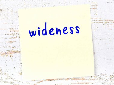 Tahta duvardaki sarı yapışkan notta el yazısı genişliği var.