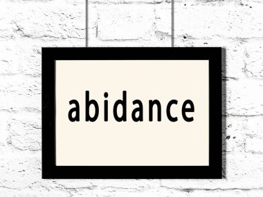 Üzerinde yazı olan siyah ahşap çerçeve beyaz tuğla duvarda asılı. 