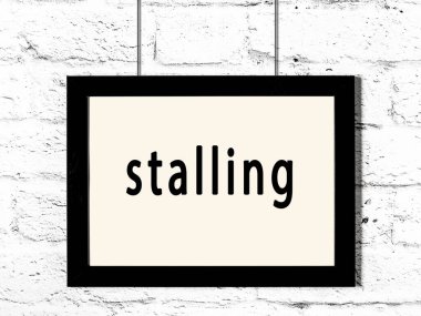 Siyah ahşap çerçeve beyaz tuğla duvarda asılı duran yazıtlar. 