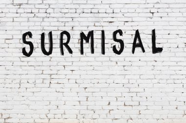 Beyaz tuğlalı duvar. Üzerinde yazı var. El yazısıyla siyah boya.