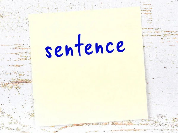 Tahta duvarda el yazısıyla yazılmış sarı yapışkan bir not var.