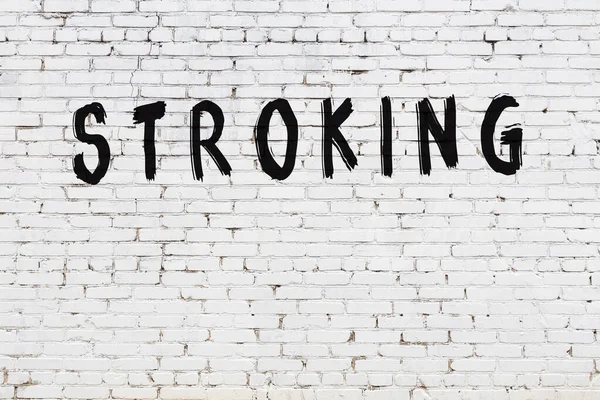 Üzerinde yazı olan beyaz tuğla duvar. Siyah boyayla yazılmış.