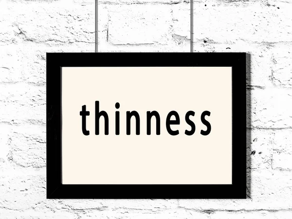 Siyah ahşap çerçeve, beyaz tuğla duvarda ince yazılar asılı. 