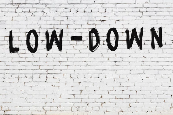 Beyaz tuğla duvarda siyah boyayla yazılmış..