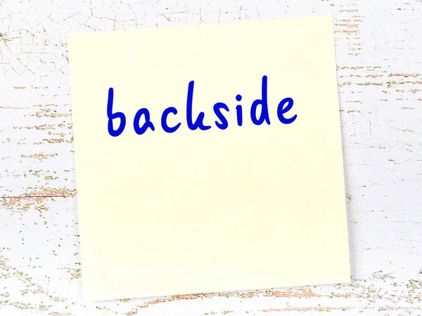 Ahşap duvarda el yazısıyla yazılmış arka tarafında sarı yapışkan bir not var.