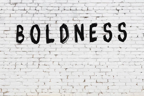 Siyah boyayla yazılmış beyaz tuğlalı bir duvar.