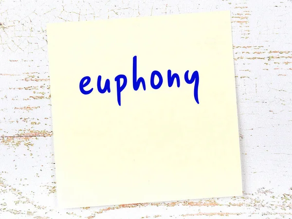 Euphony 'i hatırlatma kavramı. Tahta duvarda üzerinde yazı olan sarı yapışkan kağıt.