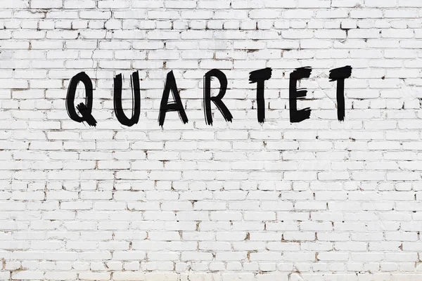 Beyaz tuğla duvara siyah boya ile yazılmış bir dörtlü yazı..