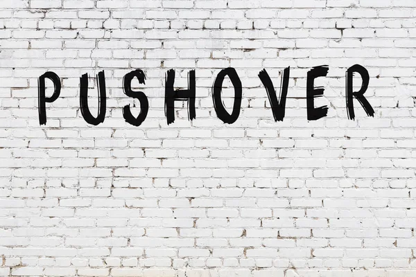 Beyaz tuğlalı duvara siyah boya ile yazılmış bir yazı..