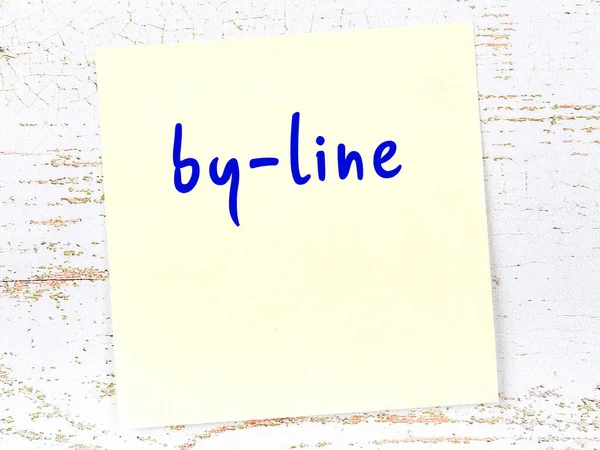 Tahta duvarda el yazısıyla yazılmış sarı yapışkan bir not var.