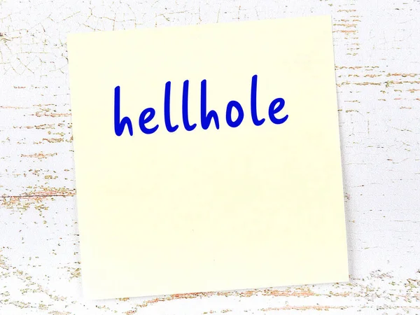 Tahta duvardaki sarı yapışkan notta el yazısıyla yazılmış cehennem deliği var.