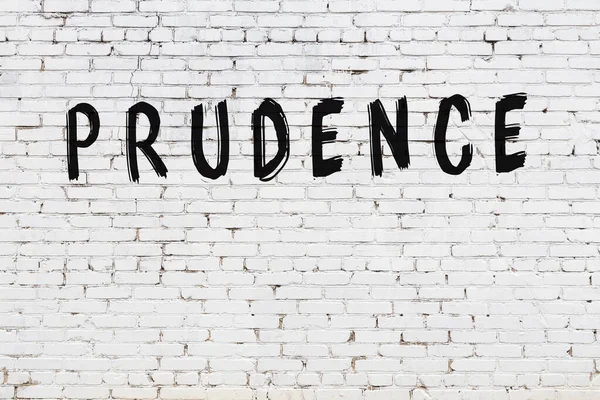 Beyaz tuğla duvarda siyah boyayla yazılmış bir yazıt..