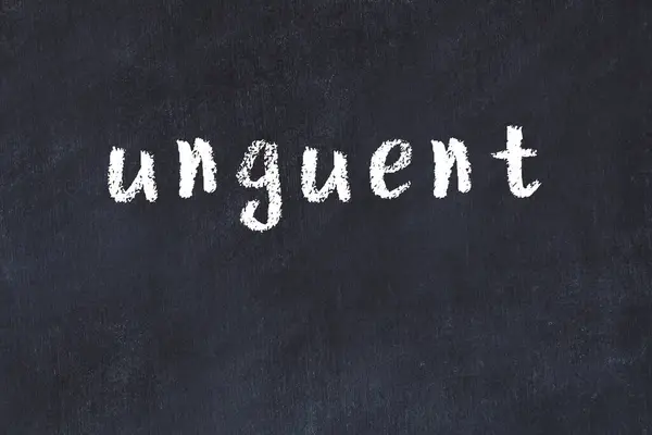 Tebeşir el yazısıyla yazılmış merhem siyah masada.