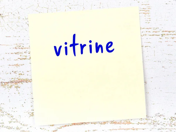 Tahta duvardaki sarı yapışkan notta el yazısıyla yazılmış vitrin var.