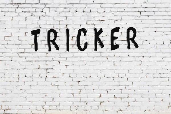 Beyaz tuğlalı duvar, siyah boyalı el yazısı.