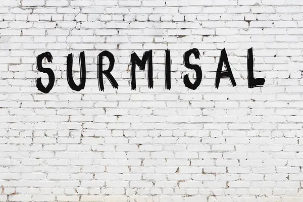 Beyaz tuğlalı duvar. Üzerinde yazı var. El yazısıyla siyah boya.