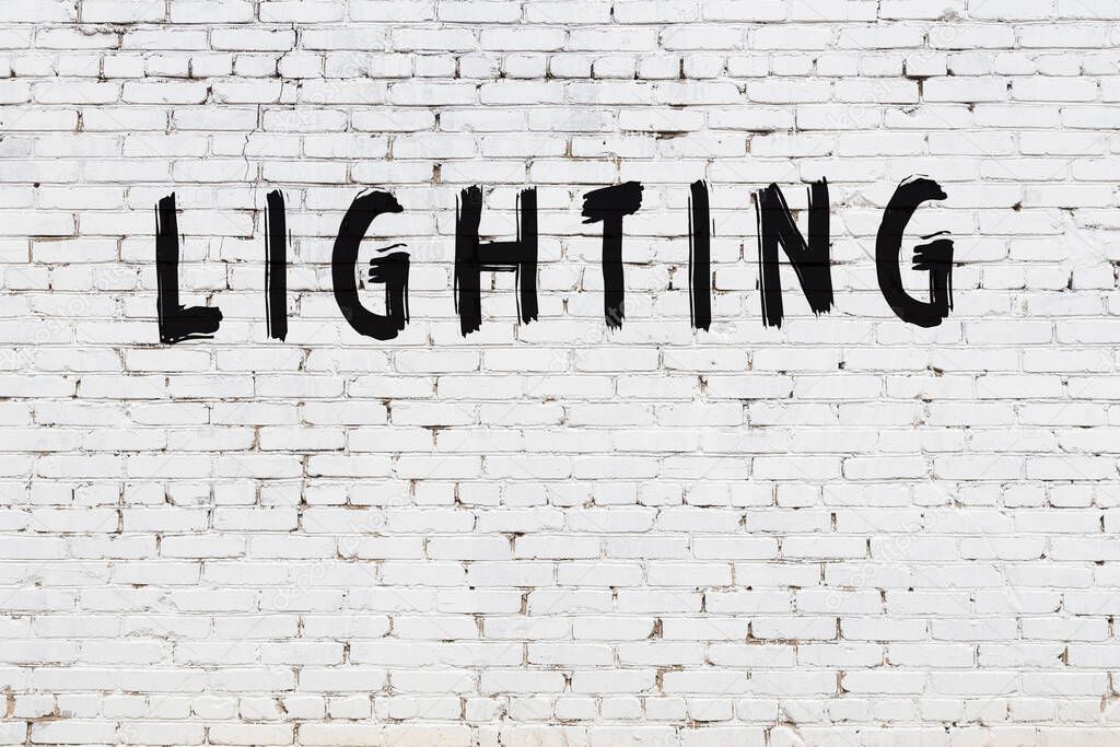 Inscription lighting written with black paint on white brick wall.