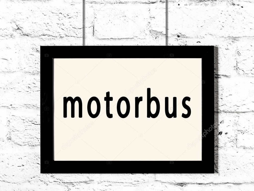 Black wooden frame with inscription motorbus hanging on white brick wall 