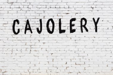 Beyaz tuğlalı duvara siyah boya ile yazılmış bir yazıt..