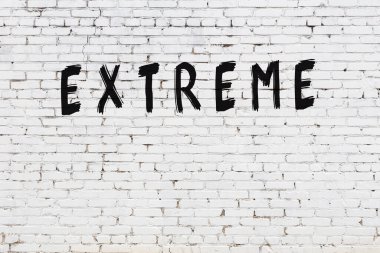 Beyaz tuğlalı duvar, üzerinde siyah boya ile el yazısı var.