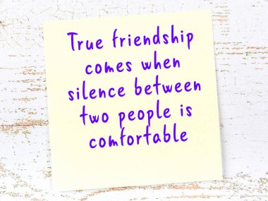 Tahta duvarda asılı sarı yapışkan nota elle yazılmış bilgece bir alıntı.