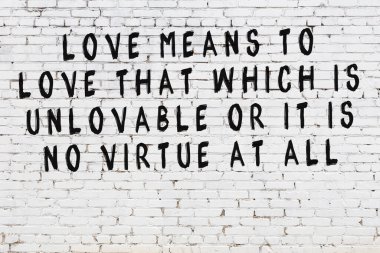 Beyaz tuğla duvara zekice alıntılar yazılı siyah bir yazı.