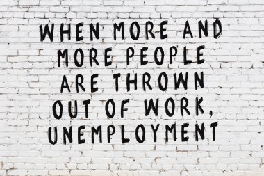 Beyaz tuğla duvara zekice alıntılar yazılı siyah bir yazı.