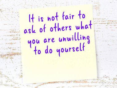 Sarı yapışkan not, ahşap duvarda el yazısıyla yazılmış zekice bir alıntıyla.