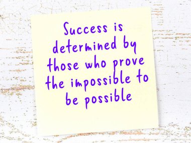 Sarı yapışkan not, ahşap duvarda el yazısıyla yazılmış zekice bir alıntıyla.