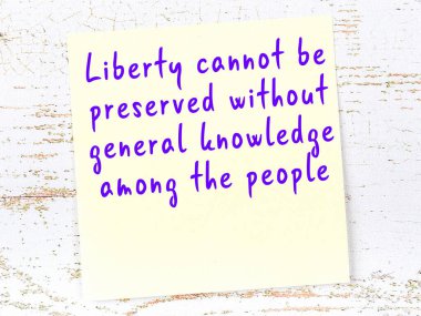 Tahta duvarda asılı sarı yapışkan nota elle yazılmış bilgece bir alıntı.
