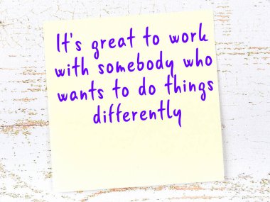 Sarı yapışkan not, ahşap duvarda el yazısıyla yazılmış zekice bir alıntıyla.