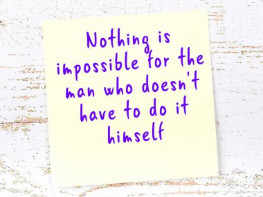 Sarı yapışkan not, ahşap duvarda el yazısıyla yazılmış zekice bir alıntıyla.