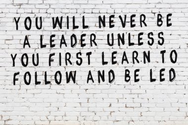 Üzerinde mantıklı alıntıların yazılı olduğu siyah boyanmış beyaz tuğla duvar.