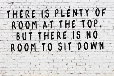 Beyaz tuğla duvara zekice alıntılar yazılı siyah bir yazı.