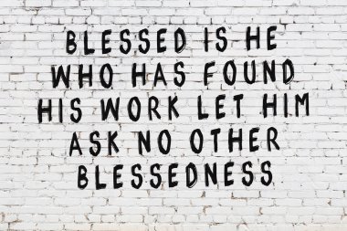 Beyaz tuğla duvara zekice alıntılar yazılı siyah bir yazı.