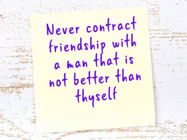 Tahta duvarda asılı sarı yapışkan nota elle yazılmış bilgece bir alıntı.