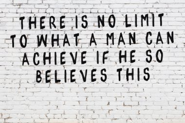 Beyaz tuğla duvara zekice alıntılar yazılı siyah bir yazı.