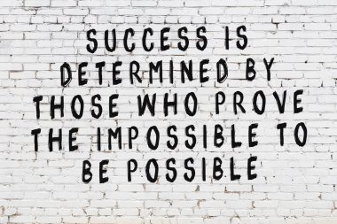 Beyaz tuğla duvara zekice alıntılar yazılı siyah bir yazı.