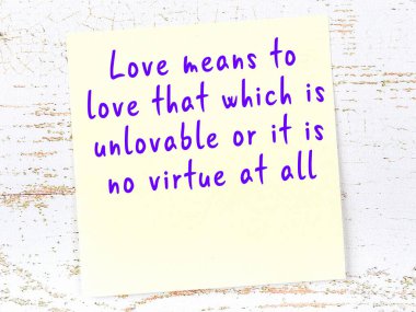 Tahta duvarda asılı sarı yapışkan nota elle yazılmış bilgece bir alıntı.