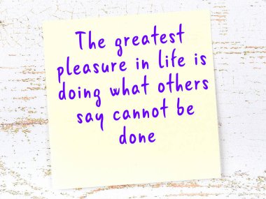 Tahta duvarda el yazısı motivasyon alıntısı olan sarı yapışkan not