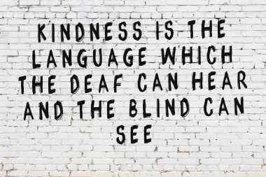 Beyaz tuğla duvara zekice alıntılar yazılı siyah bir yazı.