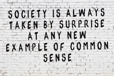 Beyaz tuğla duvara zekice alıntılar yazılı siyah bir yazı.