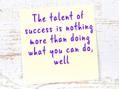 Tahta duvarda asılı sarı yapışkan nota elle yazılmış bilgece bir alıntı.