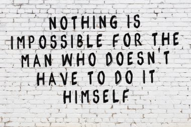 Beyaz tuğla duvara zekice alıntılar yazılı siyah bir yazı.