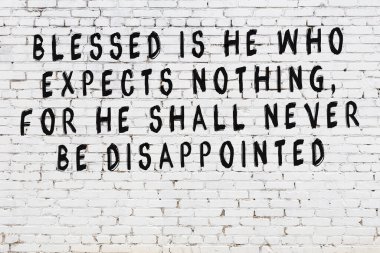 Beyaz tuğla duvar ve bilgece alıntıların yazılı olduğu siyah yazı.