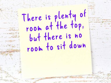 Sarı yapışkan not, ahşap duvarda el yazısıyla yazılmış zekice bir alıntıyla.