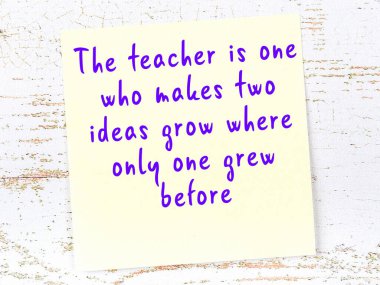 Tahta duvarda asılı sarı yapışkan nota elle yazılmış bilgece bir alıntı.