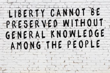 Beyaz tuğla duvara zekice alıntılar yazılı siyah bir yazı.