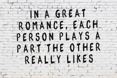 Beyaz tuğla duvara zekice alıntılar yazılı siyah bir yazı.